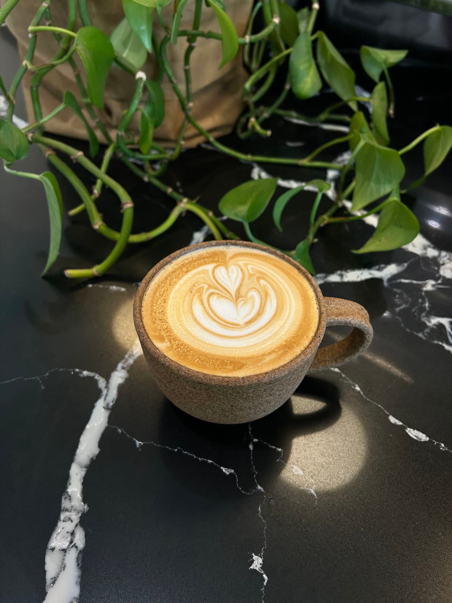 A latte in a ceramic cup on a black marble counter