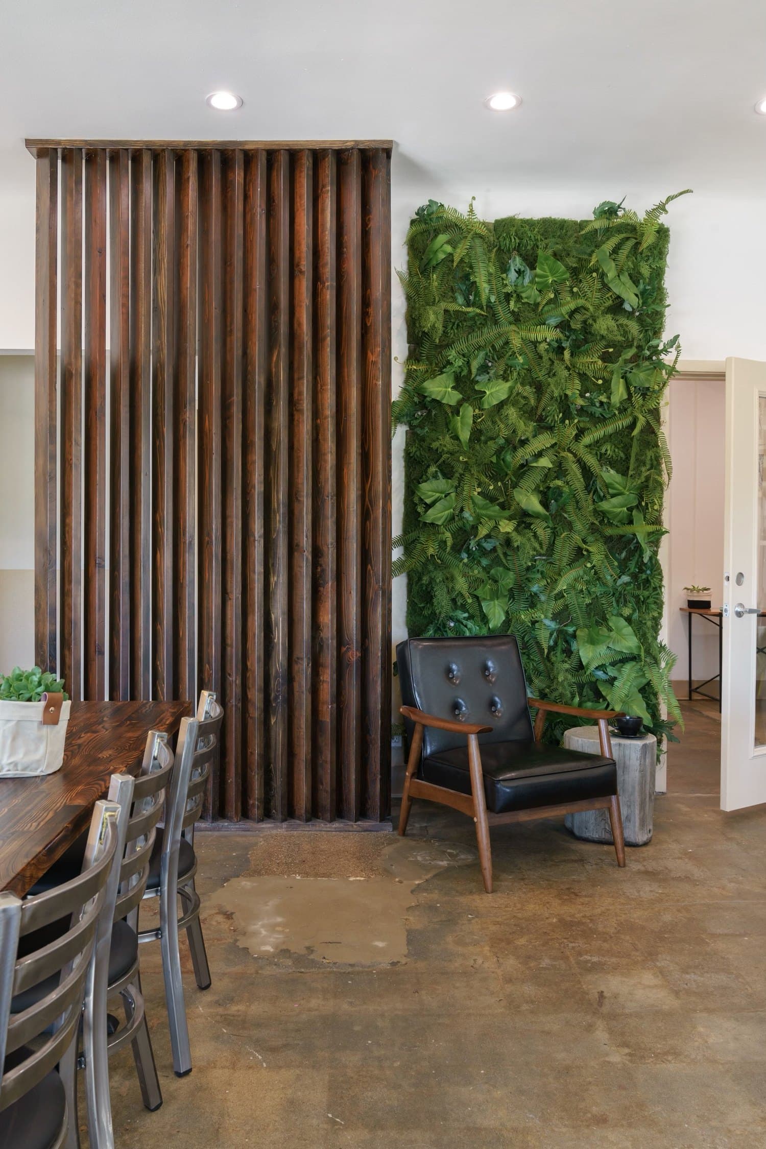A wall of live plants beside dark wood slats at Wrigley Coffee